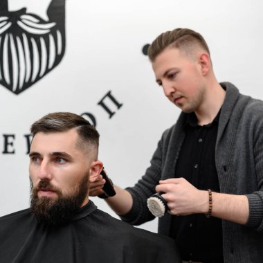 Bir berber berber dükkanında sakallı bir adamı keser. Kesici ile müşterinin kısa saç kesimi.