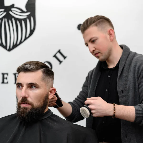 Bir berber berber dükkanında sakallı bir adamı keser. Kesici ile müşterinin kısa saç kesimi.