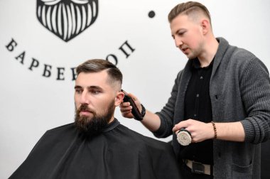 Bir berber berber dükkanında sakallı bir adamı keser. Kesici ile müşterinin kısa saç kesimi.