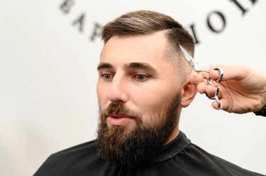 Saç kesimi ve kafa hatlarının makas ile hizalanması. Berber dükkanında kısa saç kesimi..