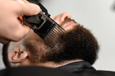 Berber dükkanında bir beyefendinin sakalını makasla kesmek. Müşteri için sahibinin sakalının kenarlarını kısaltıyorum..