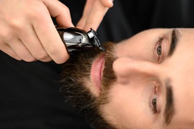 Bir berber, beyaz bir müşteri bıyığını budayarak buduyor..