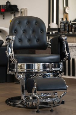 Siyah deri ve krom elementlerden yapılmış berber koltuğu. Berber dükkanındaki yeni sandalyenin önü..