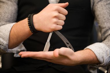 Üçgen şeklinde tehlikeli bir jilet tutan bir berbere yakın plan..