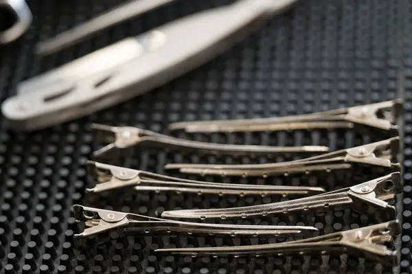 Hair clips on a black barber\'s workspace close-up.