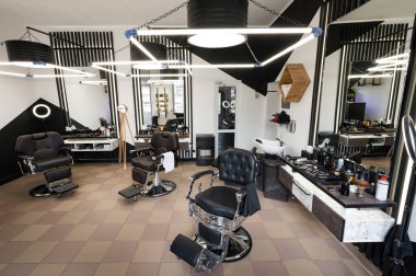 Sandalyeli bir erkek berberinin modern iç mekanı geniş açılı çekilir. LED lambalı siyah beyaz renkli bir kuaför salonunun tasarımcısı..