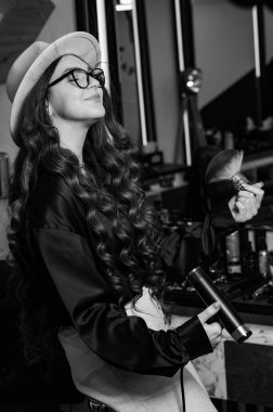 Genç bir berber kız saçını kurutucunun havasıyla siliyor. Bir kuaförün kadın portresi..