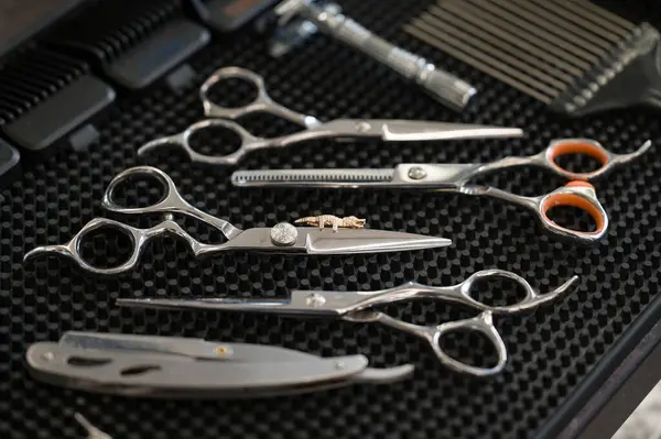 Barbers tools for mens haircuts laid out on a table close up. Set of scissors and dangerous razor for haircuts close up.
