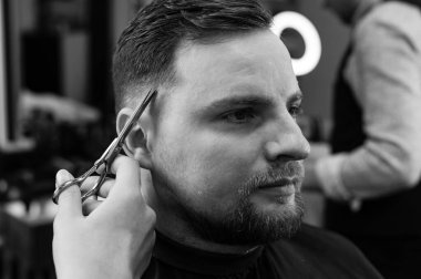 Saç kesimi ve kafa hatlarının makas ile hizalanması. Berber dükkanında kısa saç kesimi..