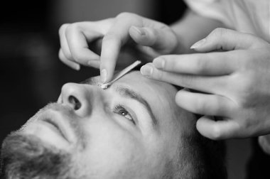 Kaşlarını aldırıyor, tüylerini aldırıyor. Berber dükkanında saç çıkarma prosedürü.