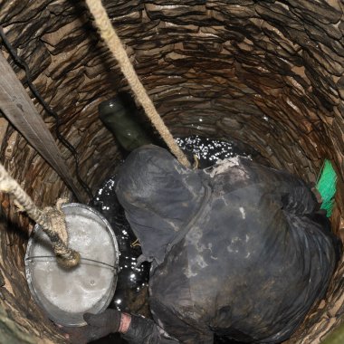 Bir adam kuyunun dibini temizledikten sonra taşları dezenfekte eder, hijyenik ve temiz su kuyularında çalışır..