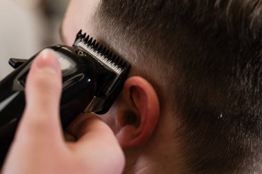 Saç kesimi ve kafa hatları saç makasıyla ve budayıcıyla aynı hizada. Berber dükkanında kısa saç kesimi..