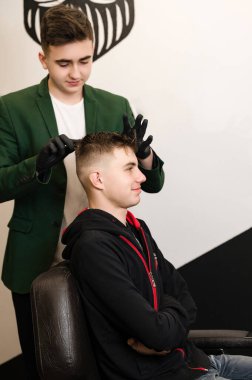 Bir el ile saç şekillendirme, bir stilist tarafından müşterinin saçını tarama. Berber dükkanındaki bir ziyaretçinin saç kesimi..