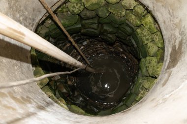 Su dolu bir köy manzarası, kuyuda bir kablo ve bir hortum var..