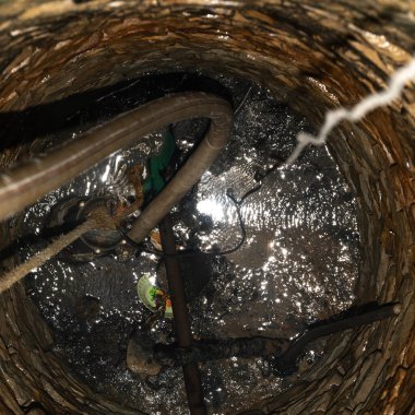 Bir köy taşla kaplıdır, ortadaki kuyunun manzarası, kuyunun içi bir boru, bir kablo ve bir elektrik kablosu..