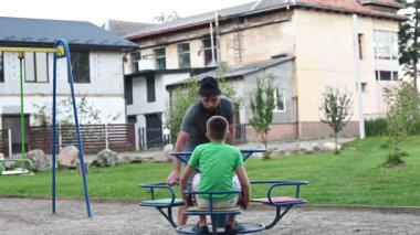 Baba oğlunu oyun parkında atlı karıncalarla, baba oğul tatilleriyle eğlendiriyor..