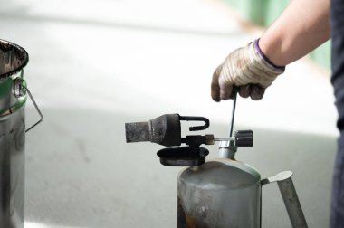 The method of heating resin in a bucket using a kerosene lamp at home, waterproofing the floor with resin. clipart