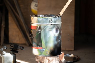 Bir adam kovada reçine ısıtmak için gaz lambası kullanır. Su yalıtımı ve reçineyle çalışır. Kendi başına bir usta..