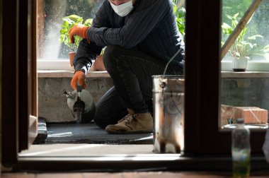 Bir adam zemini su geçirmez hale getirmek için bir rulo zemin ısıtmak için gaz lambası kullanır. Tamir ve inşaat işlerinde çalışır..