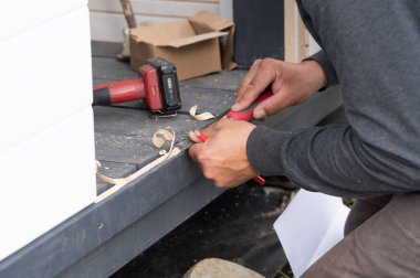 Bir adam, bir marangoz aleti kullanır, bir değirmen kesicisi, kapının altından bir eşik kesmek için, bir balkon inşaatında dakikalar.