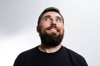 Sakallı bir adam yukarı bakar. Yüzünde tuhaf ve biraz da yaramaz bir ifade vardır..