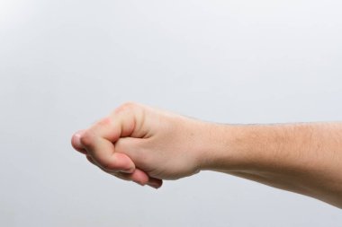 Bir insanın elinin yavaşça gevşek bir yumruğa yapışması. Görüntü basit, açık gri bir arkaplan üzerine kurulur, dikkatleri elin konumuna odaklar ve şekillendirir..
