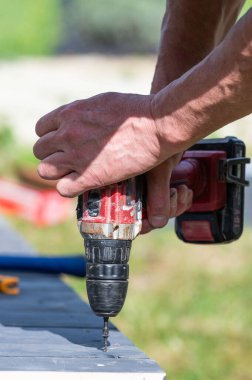 Tahta bir çardağın montajı, usta vidaları ahşap zemine yakın vidalar.