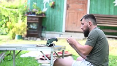 Bir adam gölgeli bir bahçede oturur ve üzüm yer, bahçede küçük bir atıştırmalık.