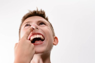 Genç bir çocuğun gülüşünü yakından çek, başka bir el nazikçe burnuna dokunsun. Görüntü neşelidir ve anlık bir neşe anı yakalar..