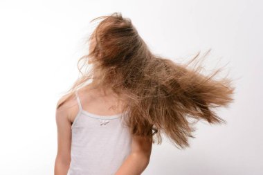 Arkadan uzun, açık kahverengi saçlı genç bir kız gösteriliyor. Saçları rüzgarlı ve dalgalı, dinamik. Sade, açık renkli bir bluz giyiyor. Arkaplan düz beyaz.