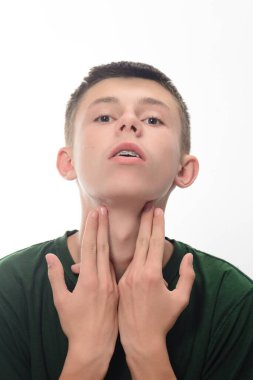 Kısa kahverengi saçlı, boğazına hafifçe dokunan genç bir adamın yakın plan portresi. Koyu yeşil bir gömlek giyiyor. Yüzündeki ifade ince ve biraz endişeli..