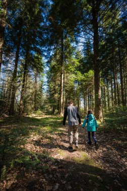 Kardeşler yemyeşil bir ormanı, uzun ağaçların arasından süzülen güneş ışığını keşfeder. El ele yürürler, etraflarındaki doğal güzelliğin tadını çıkarırlar..