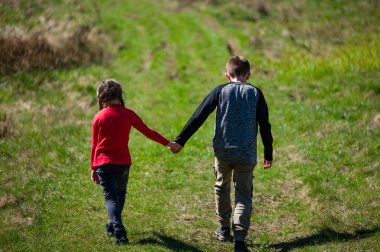 İki küçük kardeş, bir oğlan ve bir kız, yeşil bir yolda el ele yürüyorlar. Güneş ışıl ışıl parlıyor, sahneye sıcak bir parıltı saçıyor. Yürek ısıtan bir kardeş bağı..