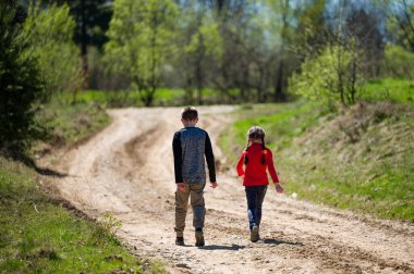 Bir çift kardeş, güneşli bir günün tadını çıkararak kırsal bir yolda yürüyor. İlahi ayar doğanın güzelliğini gözler önüne seriyor. Onların tasasız yürüyüşleri çocukluk masumiyetini simgeler..