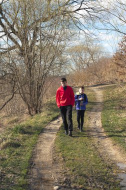 İki genç çocuk kırsal alanda bir patikada yürüyor. Yol toprak ve çevreleyen bitki örtüsü kıt, bu da baharın geldiğini gösteriyor. Çocuklar keyifli bir yürüyüş yapıyor gibi görünüyorlar..