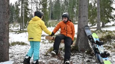 Karlı bir orman ortamında ağaçtan salıncakta sallanan iki çocuk. Karla kaplı zemin ve etraflarını saran uzun ağaçlar. Snowboard 'lar ağaç gövdesinde dinleniyor..