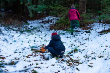 İki çocuk karlı bir ormandalar. Biri küçük bir ateşe bakarken diğeri uzaktan seyrediyor. Sahne huzurlu ve kışlık..
