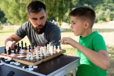 Bir adam ve genç bir çocuk park masasında satranç oynuyorlar. Babası dikkatle izlerken, çocuk bir hamle yapıyor. Birlikte iyi vakit geçiriyorlar..