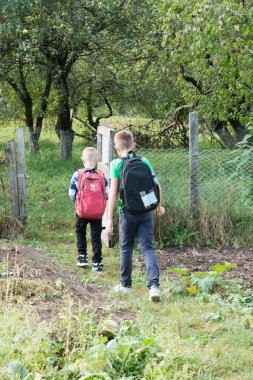 Sırt çantalı iki genç, yemyeşil bahçelerle çevrili küçük bir ahşap kapıdan bahçeye ya da bahçeye doğru yürür. Ağaçlar tepemizde. Keşif ve çocukluğa odaklanmış.