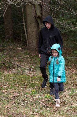 İki genç maceracı, serin bir sonbahar öğleden sonrası serin hava ve keşiflerin neşesini kucakladıkları uzun ağaçlarla çevrili gür bir ormanda yürür..