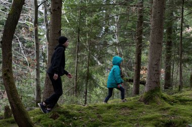 İki çocuk, uzun ağaçlar ve canlı yosunlarla çevrili sakin bir ormanda serin bir günde maceranın ruhunu somutlaştırıyor..
