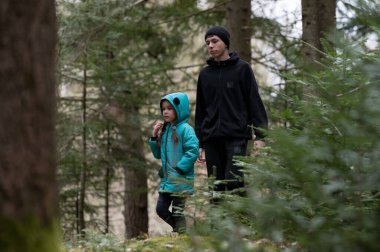 Yükselen ağaçların ve yemyeşil otlakların arasında, iki yoldaş ormanı keşfederken, kendilerini açık havanın güzelliğine daldırarak sessiz bir anı paylaşıyorlar..