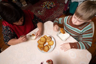 İki insan dantel masa örtüsüyle süslenmiş bir masada taze aperatiflerin tadını çıkarıyor. Sıcak atmosfer neşe ve beraberlik yayar, mutfak deneyimini güçlendirir..