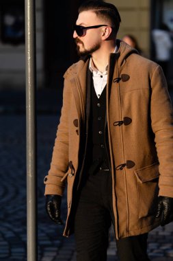 Şık bir birey, günbatımının altın parıltısıyla mükemmel bir şekilde vurgulanmış, kendine güveni ve tarzıyla büyüleyici bir kaldırım taşı yolunda yürüyor..