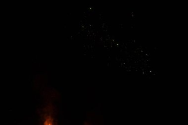 Parlak havai fişekler, koyu bir gökyüzüne karşı çeşitli renklerde patlıyor, gece canlı bir kutlamada seyircilerin tezahürat yaptığı kıvılcımlar ve ışıklar yağıyor..