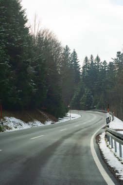 Kıvrımlı, karla kaplı bir yol sık bir ormanın içinden geçiyor, kaşifleri sakin bir yolculuğun tadını çıkarmaya davet ediyor. Etrafı kıtır kıtır mavi gökyüzünün altında yükselen yeşil ağaçlarla çevrili..
