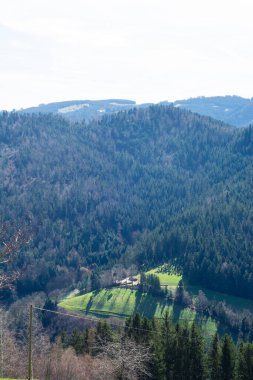 Verimli yeşil alanlar vadi zemininde uzanır, yüksek dağların arasında yuva yapar, güneş ışığı manzarada dans ederken, manzaralı bir kırsal manzara yaratır.