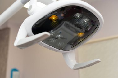 Bir diş kliniğinde, gelişmiş bir lamba, hasta rahatlığı ve bakımını sağlarken dişçiye titiz bir iş yapması için odaklanmış ışıklandırma sağlar..