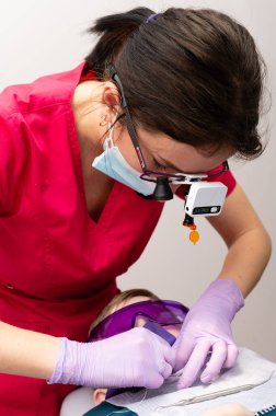 Kendini işine adamış bir diş hekimi, genç bir hastayı dikkatlice tedavi ediyor. Klinik ortamda iyi bir ağız temizliğini desteklerken güvenli ve rahat bir deneyim sağlıyor..