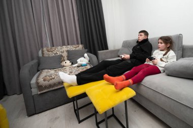 İki kardeş keyifli bir akşamı paylaşıyor, rahat bir koltukta oyun oynamaya dalmış, video oyunlarına ve birbirlerine olan sevgilerini sıcak, davetkar bir yerde sergiliyorlar..